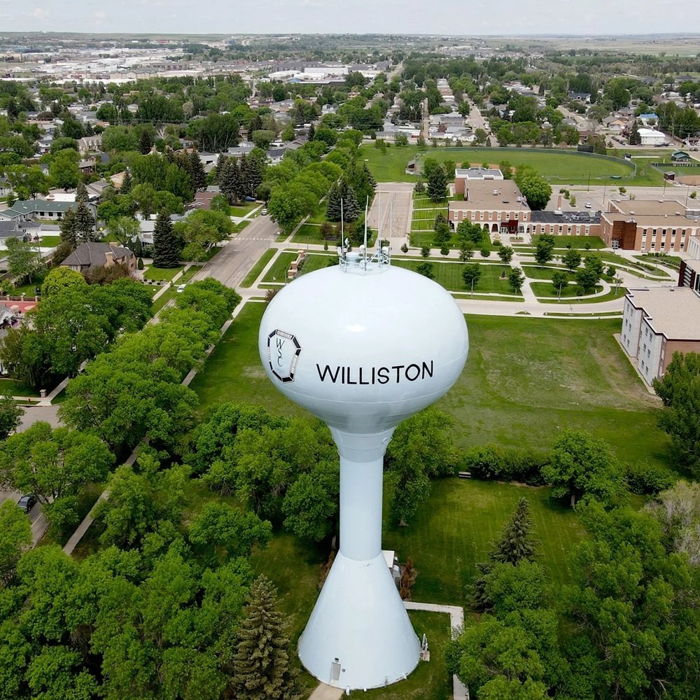 Industrial broker reviewing warehouse site options with client near active Williston operations yard